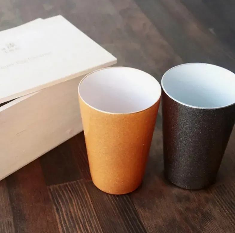 Pair of urushi-coated cups, orange and dark brown, beside their wooden gift box