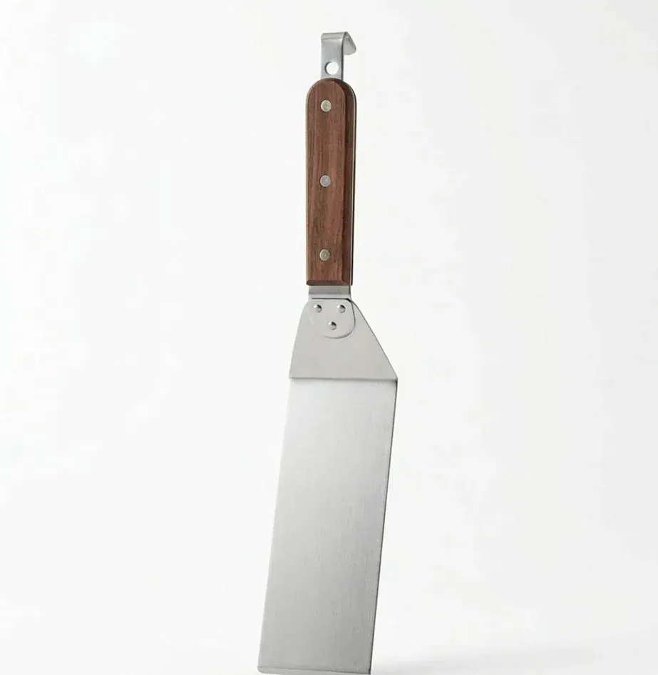 Stainless steel gyoza turner with a wooden handle on a white ground